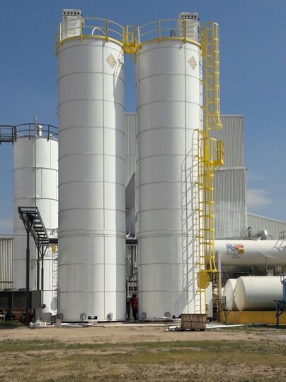 three white silos next to a warehouse 